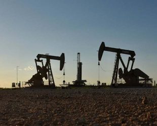 FILE PHOTO: Pump jacks operate in front of a drilling rig in an oil field in Midland, Texas U.S. August 22, 2018. Picture taken August 22, 2018. REUTERS/Nick Oxford/File Photo